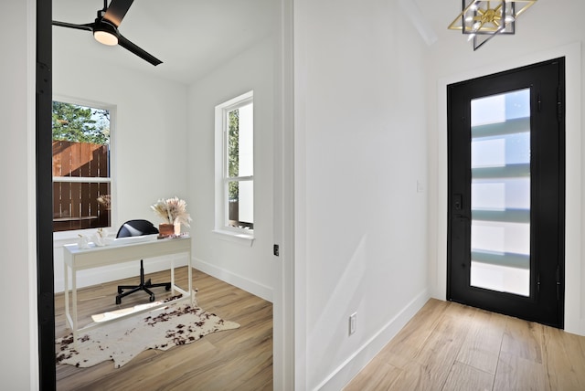 office space with ceiling fan with notable chandelier, a healthy amount of sunlight, and light wood-type flooring