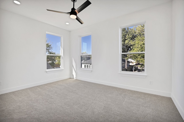 carpeted spare room featuring a wealth of natural light and ceiling fan