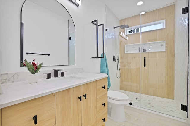 bathroom featuring vanity, toilet, and a shower with shower door