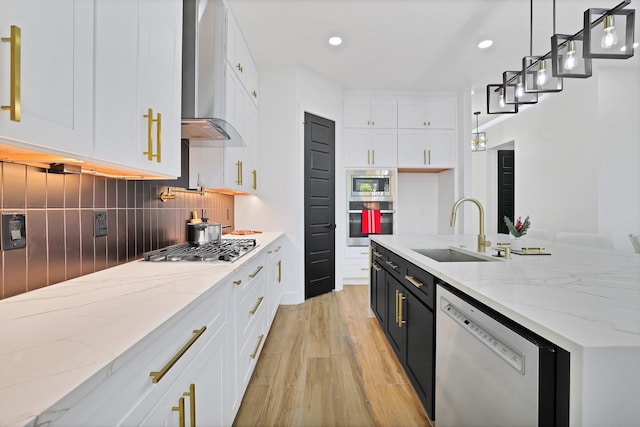 kitchen featuring stainless steel appliances, sink, wall chimney range hood, and white cabinets