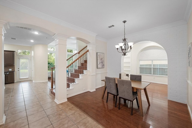 dining area with an inviting chandelier, ornamental molding, a wealth of natural light, and light hardwood / wood-style flooring