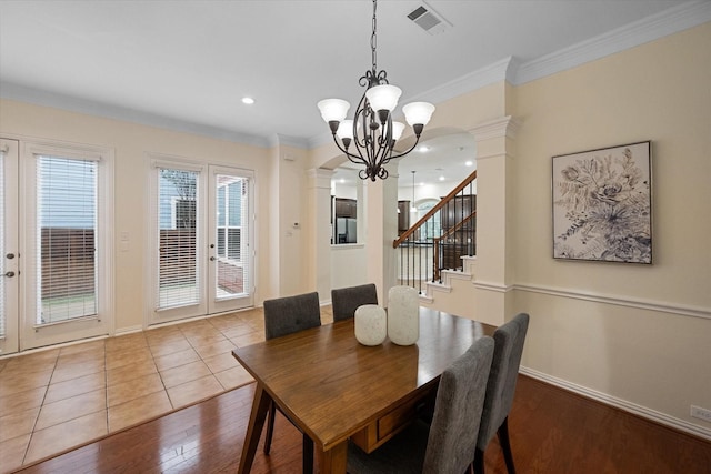 dining room with french doors, ornate columns, ornamental molding, an inviting chandelier, and hardwood / wood-style floors