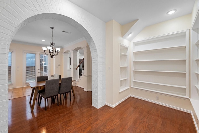 dining room featuring built in shelves, a chandelier, crown molding, and dark wood-type flooring