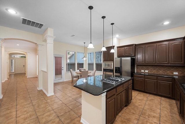 kitchen with pendant lighting, a center island, ornate columns, dark brown cabinets, and stainless steel appliances