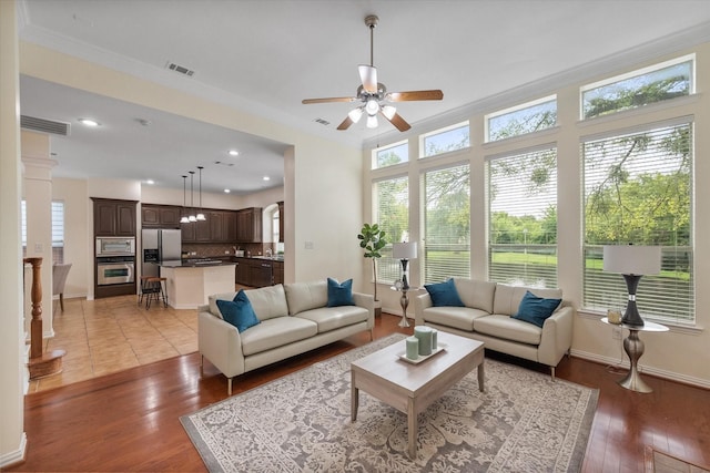 living room featuring ceiling fan, light wood-type flooring, and crown molding