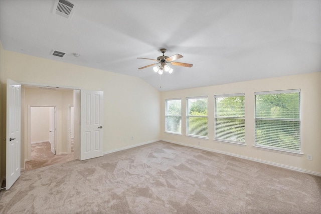 carpeted empty room with ceiling fan, plenty of natural light, and lofted ceiling