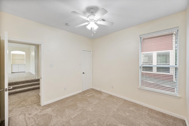 carpeted spare room featuring ceiling fan