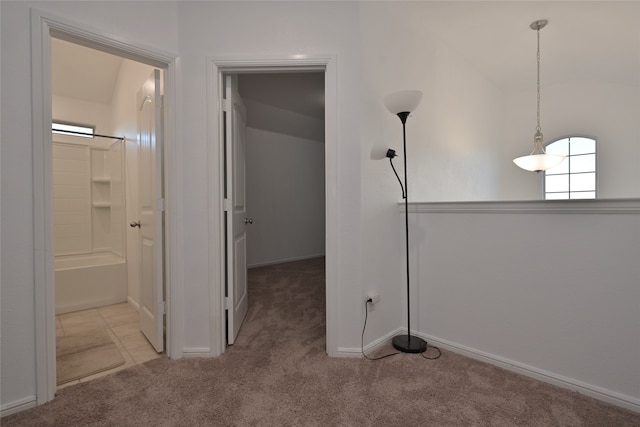 hallway featuring light carpet and vaulted ceiling