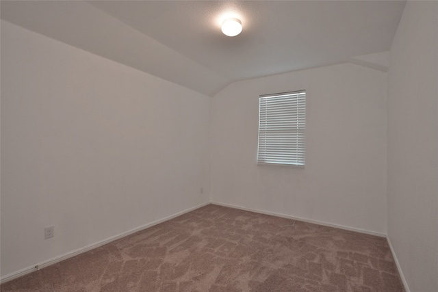 carpeted spare room with lofted ceiling