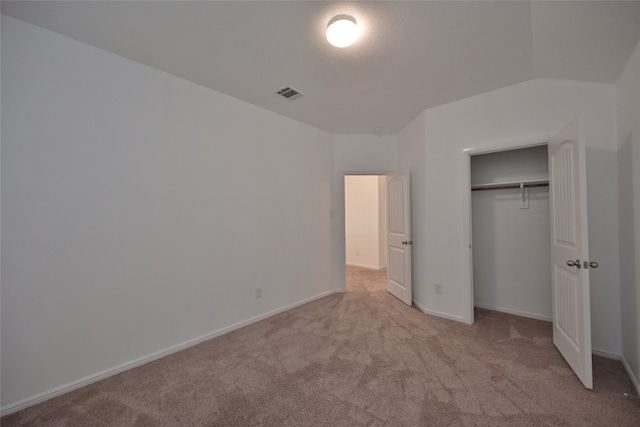 unfurnished bedroom featuring vaulted ceiling, light carpet, and a closet