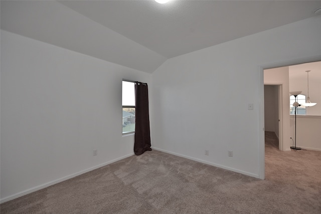 carpeted empty room with lofted ceiling