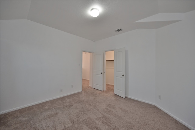 unfurnished room featuring light carpet and vaulted ceiling