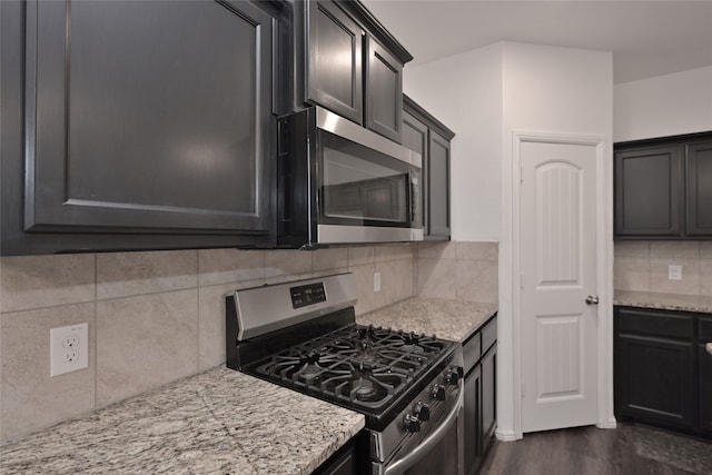 kitchen featuring dark hardwood / wood-style flooring, light stone countertops, appliances with stainless steel finishes, and tasteful backsplash