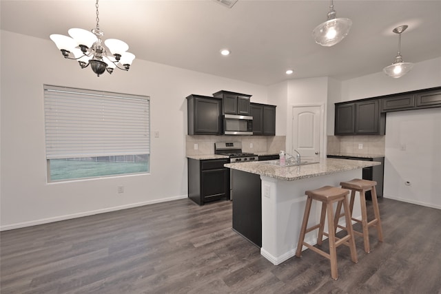 kitchen with hanging light fixtures, stainless steel appliances, a kitchen island with sink, and dark hardwood / wood-style floors