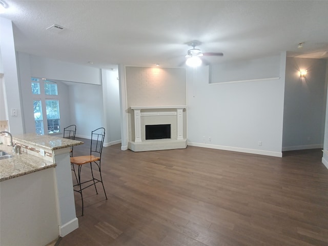 living room featuring a textured ceiling, dark hardwood / wood-style floors, ceiling fan, and sink