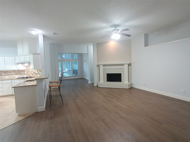 unfurnished living room with a textured ceiling, dark hardwood / wood-style flooring, and ceiling fan