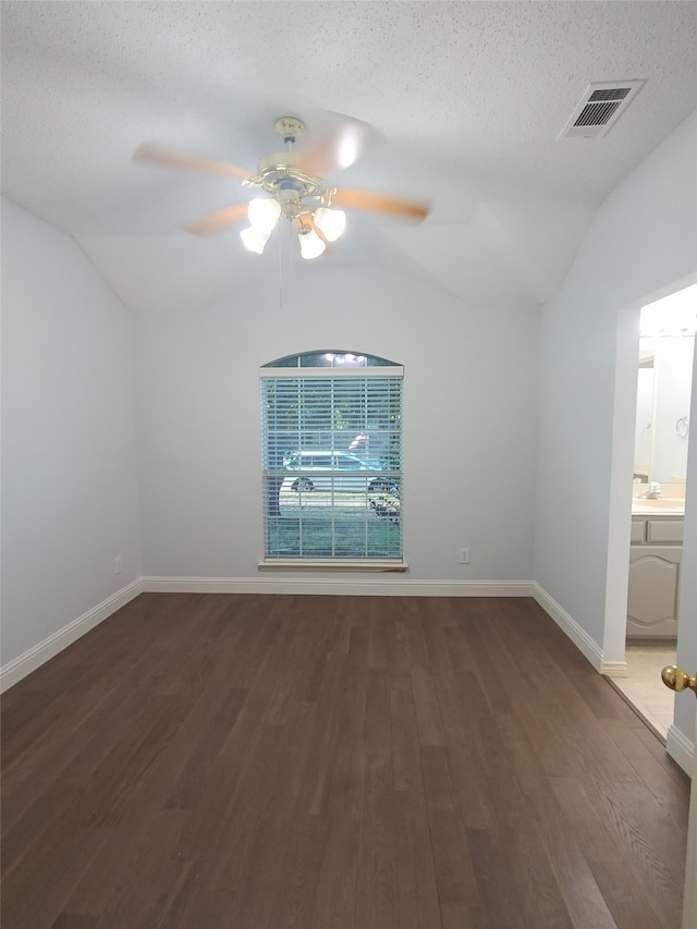 spare room featuring dark hardwood / wood-style floors, ceiling fan, a textured ceiling, and vaulted ceiling