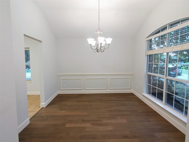 unfurnished dining area with dark hardwood / wood-style flooring, lofted ceiling, and an inviting chandelier