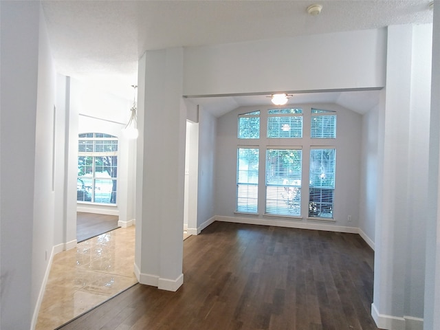 interior space featuring a textured ceiling, dark wood-type flooring, and lofted ceiling