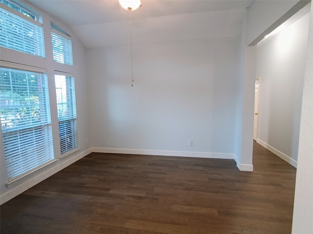 spare room with dark wood-type flooring and vaulted ceiling