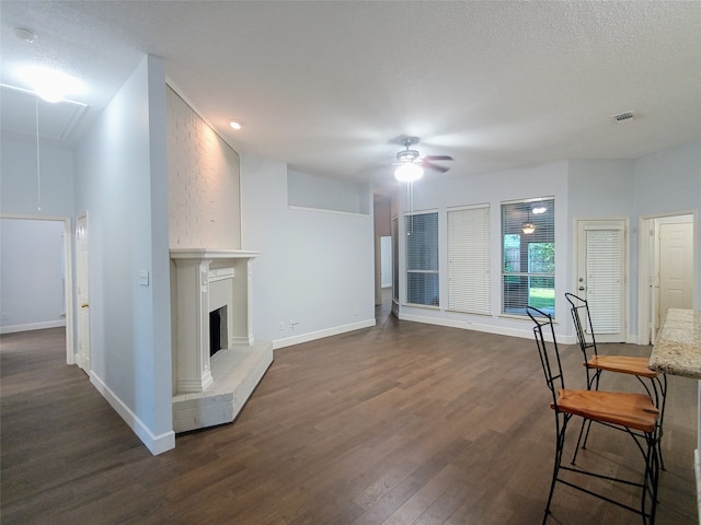 living room with ceiling fan, dark hardwood / wood-style flooring, and a textured ceiling