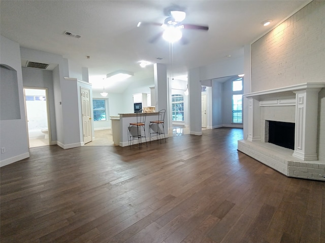 unfurnished living room with dark hardwood / wood-style flooring, a brick fireplace, and ceiling fan