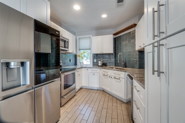 kitchen featuring tasteful backsplash, stainless steel appliances, sink, stone counters, and white cabinets