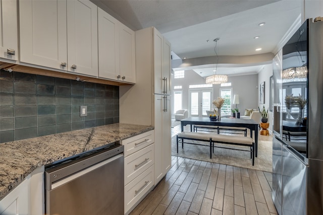 kitchen with backsplash, white cabinetry, light wood-type flooring, and stainless steel appliances