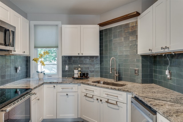 kitchen featuring backsplash, white cabinetry, sink, and stainless steel appliances