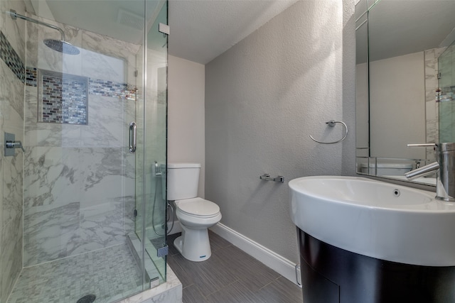 bathroom featuring a shower with door, tile patterned floors, sink, toilet, and a textured ceiling