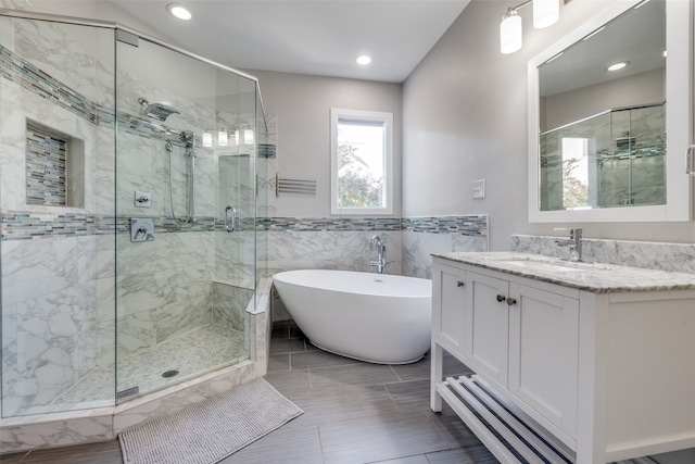 bathroom featuring vanity, tile walls, and shower with separate bathtub