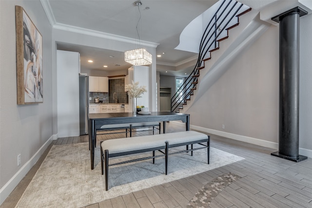 dining space featuring light hardwood / wood-style floors, ornamental molding, and an inviting chandelier