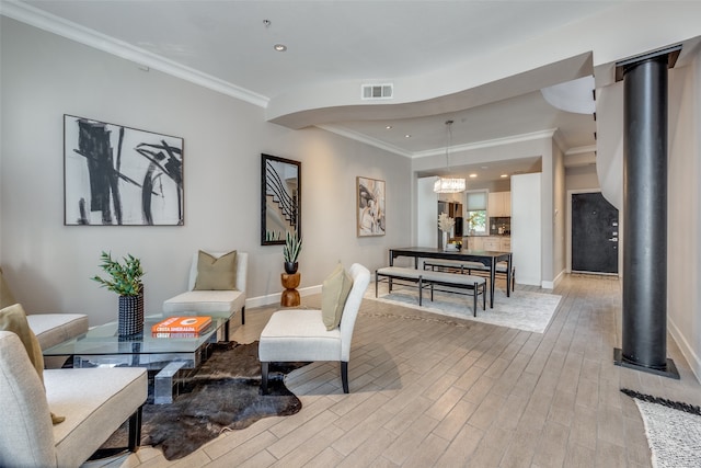 living area featuring light hardwood / wood-style floors, an inviting chandelier, and crown molding