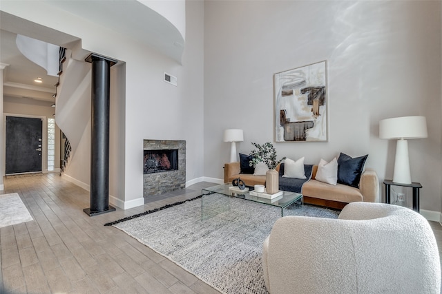 living room featuring a fireplace, a towering ceiling, and light hardwood / wood-style floors