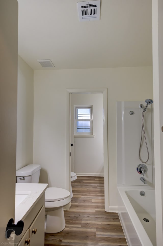 full bathroom featuring hardwood / wood-style floors, vanity, bathtub / shower combination, and toilet