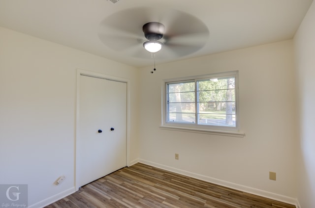 unfurnished bedroom featuring ceiling fan, wood-type flooring, and a closet