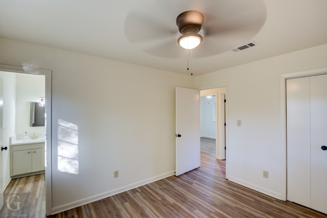 unfurnished bedroom featuring sink, ensuite bath, ceiling fan, light hardwood / wood-style floors, and a closet