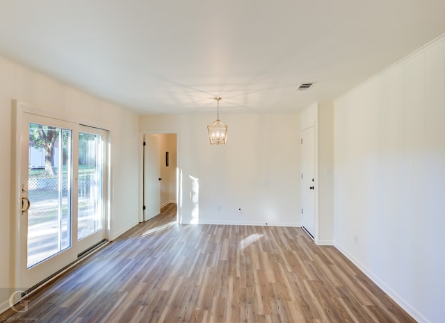 empty room with wood-type flooring and an inviting chandelier