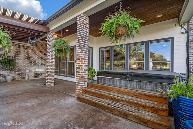 view of patio / terrace featuring a porch and a hot tub