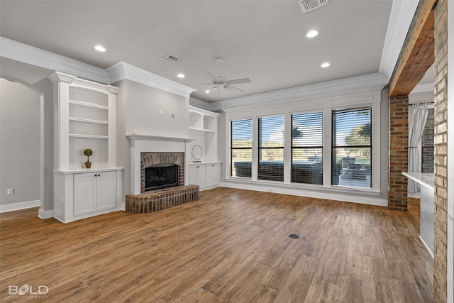 unfurnished living room with ceiling fan, a fireplace, ornamental molding, and light hardwood / wood-style flooring