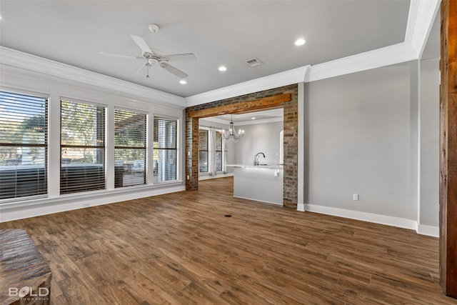 unfurnished living room featuring plenty of natural light, dark hardwood / wood-style flooring, crown molding, and ceiling fan with notable chandelier