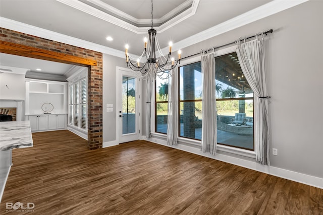 unfurnished dining area with a fireplace, an inviting chandelier, crown molding, and dark wood-type flooring