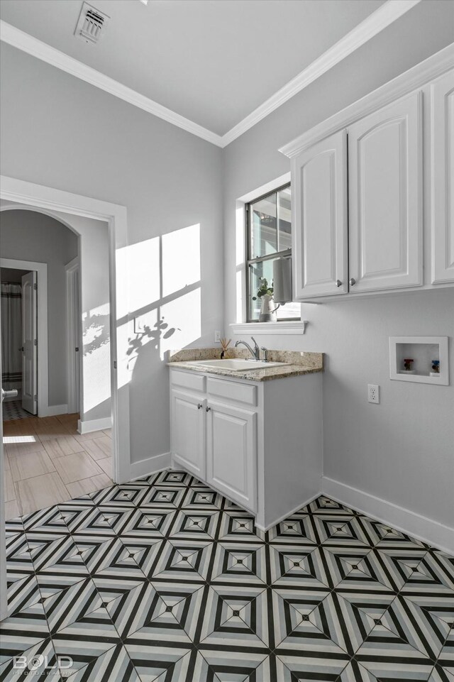 kitchen featuring white cabinets, ornamental molding, and sink