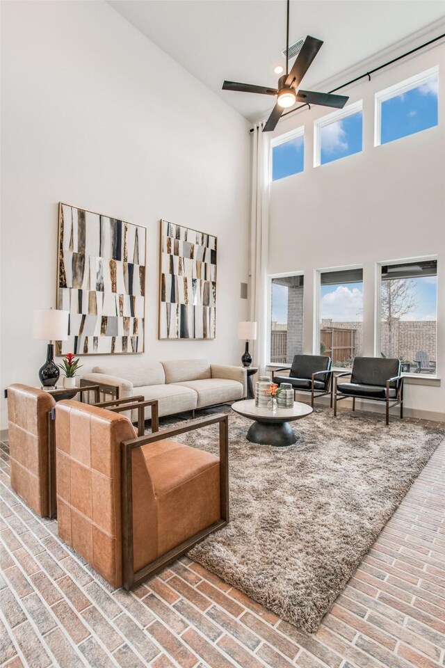 living room featuring ceiling fan and a towering ceiling