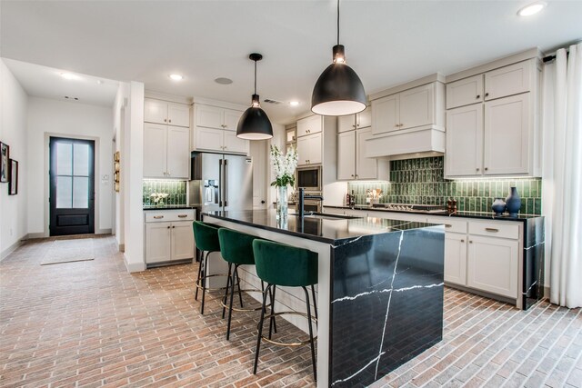 kitchen with backsplash, pendant lighting, a center island with sink, white cabinets, and appliances with stainless steel finishes