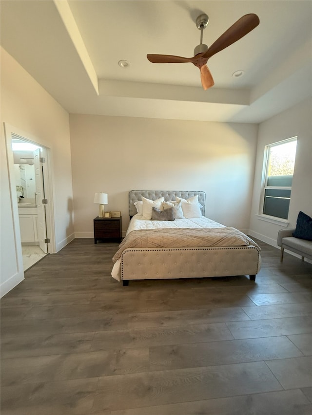 bedroom featuring a tray ceiling, dark wood-type flooring, ceiling fan, and ensuite bathroom