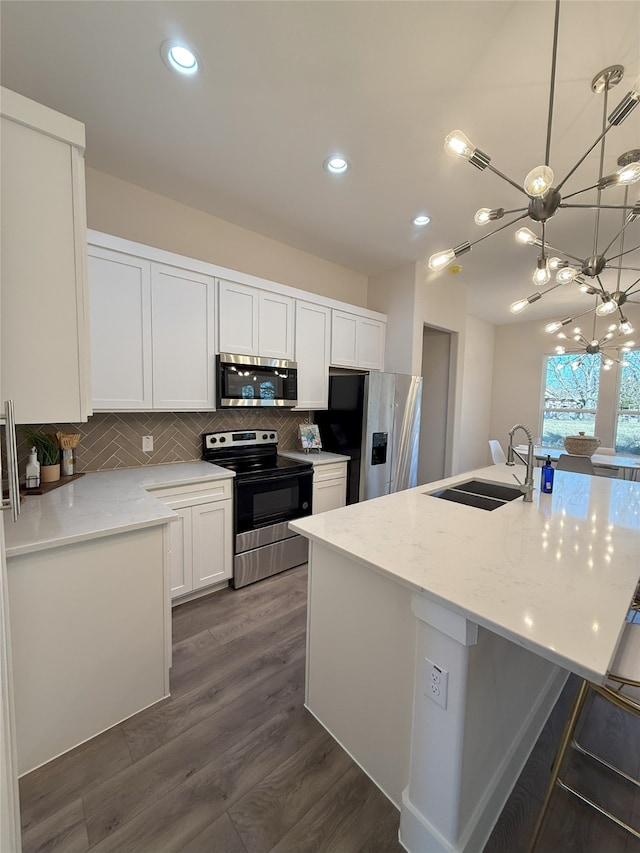 kitchen with white cabinetry, sink, backsplash, stainless steel appliances, and light stone countertops