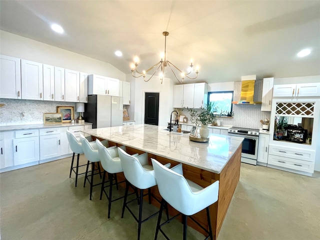 kitchen featuring a center island with sink, wall chimney exhaust hood, white cabinetry, and stainless steel appliances