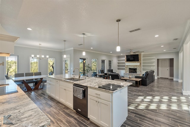 kitchen featuring sink, white cabinetry, hanging light fixtures, light stone counters, and an island with sink