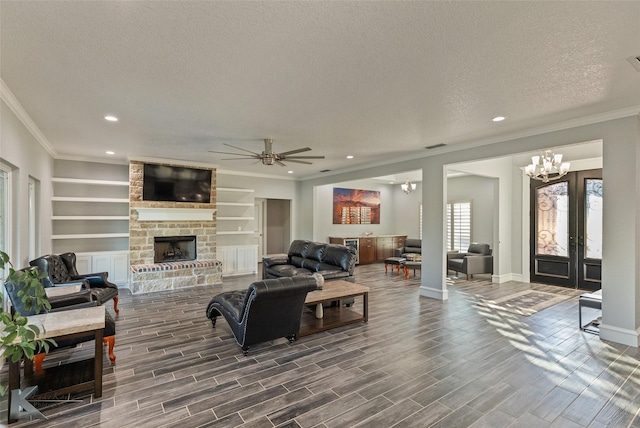 living room featuring dark hardwood / wood-style floors, a fireplace, crown molding, a textured ceiling, and built in shelves